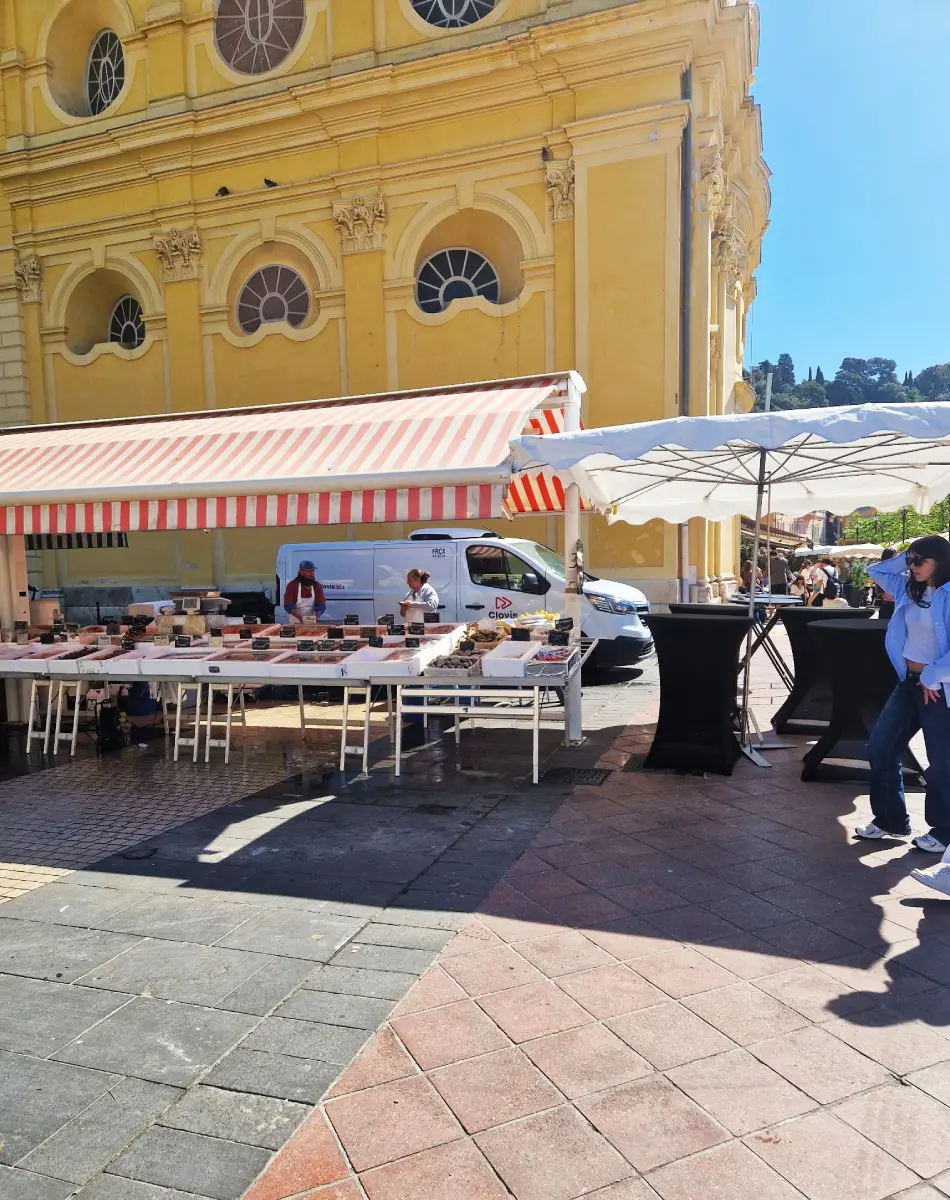 Marché en plein air avec étals et église jaune